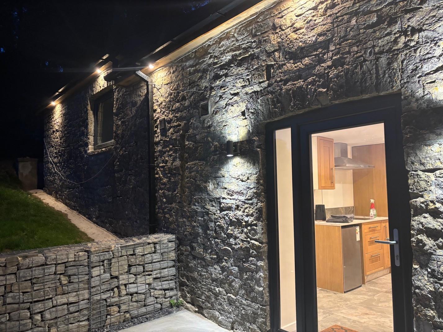 The Barn lit up after dark, with the kitchen visible through the open door